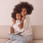 mãe negra com seu filho negro, se abraçando.